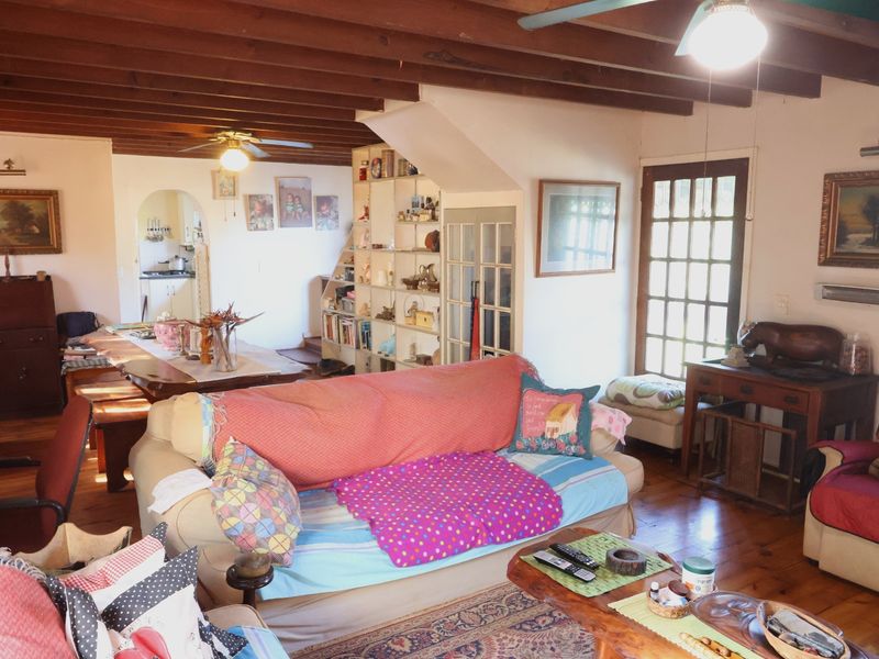 Open plan living and dining area featuring exposed timber ceiling beams, hardwood flooring, and direct access to the garden through a glass-paned door.