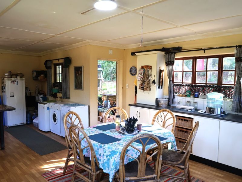 Open-plan kitchen and dining area featuring built-in cabinetry, laminate flooring, and direct access to the outdoor garden space.