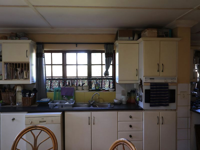 A functional kitchen featuring built-in cabinetry, a double sink, integrated oven, and a window providing natural light.