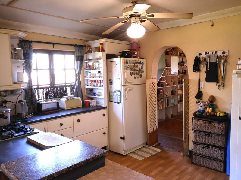 A dated kitchen featuring built-in cabinetry, a gas hob, and an arched doorway leading to an adjacent storage or pantry area.