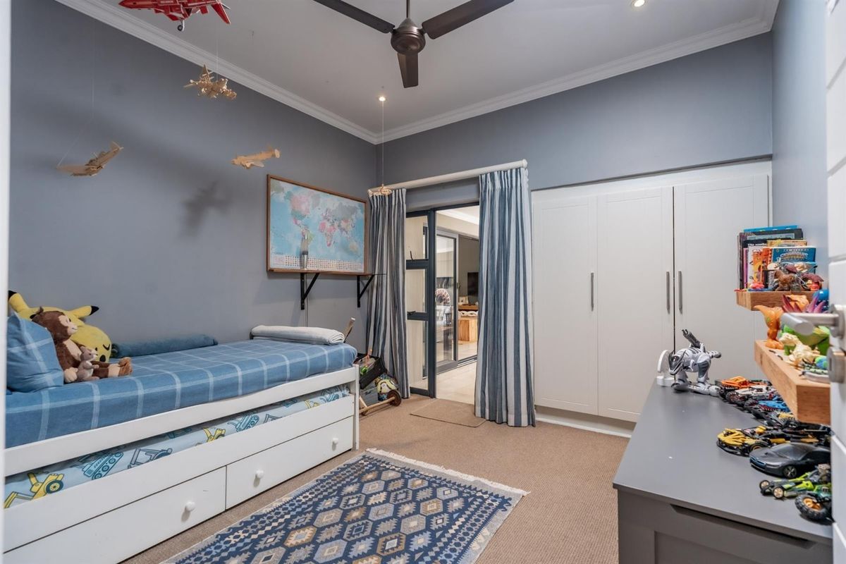 A well-maintained bedroom featuring built-in cabinetry, a ceiling fan, and direct access to an adjacent living space through a glass-paneled door.