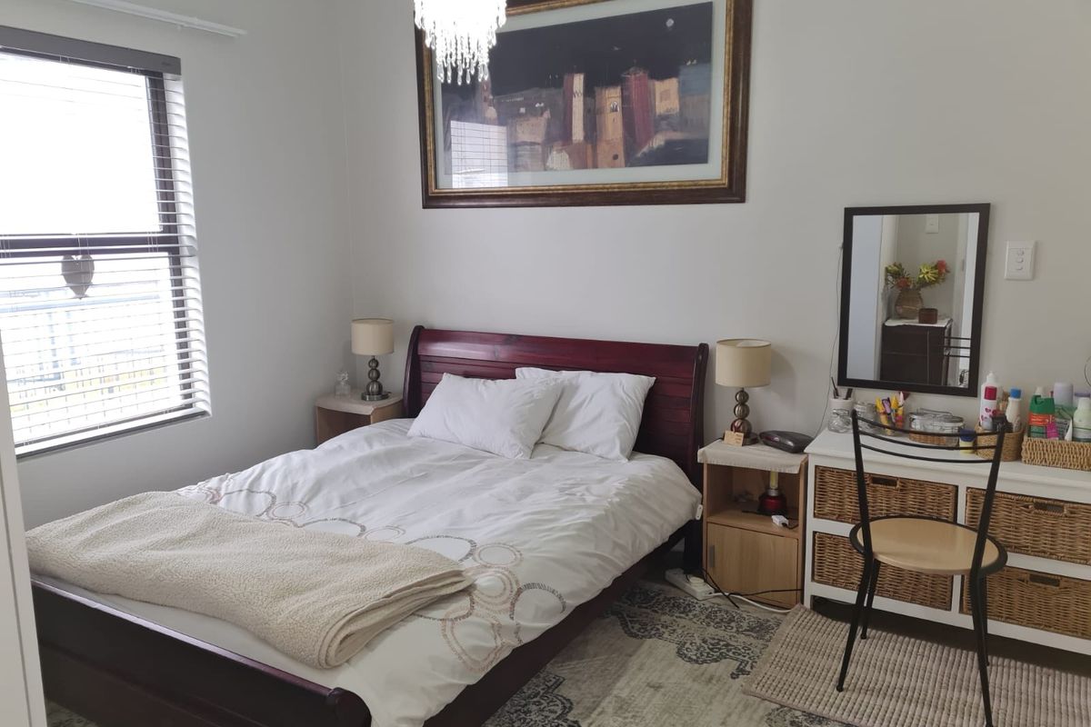 A well-maintained bedroom featuring a window with fitted blinds, neutral wall finishes, and a central light fixture.