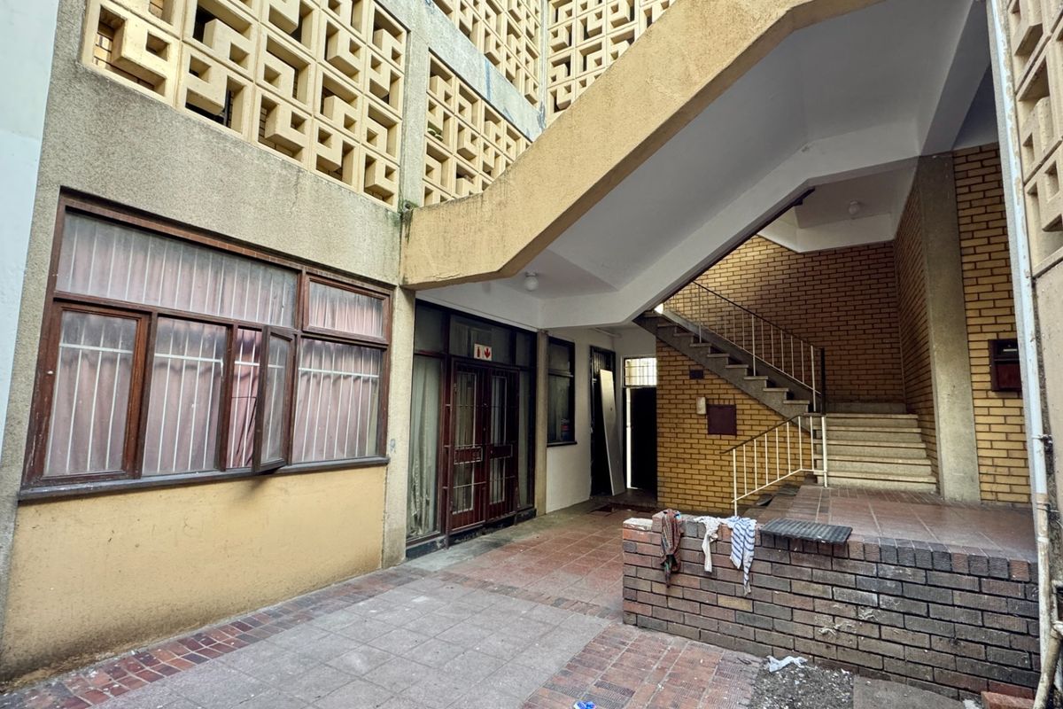 Exterior courtyard area featuring a concrete staircase, brick masonry, and decorative breeze block screening, providing access to the building entrance.