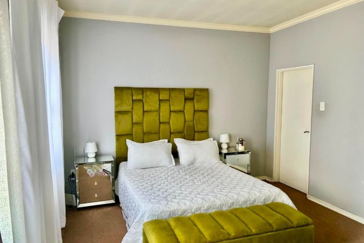 A well-maintained bedroom featuring neutral wall tones, crown molding, and carpeted flooring, providing a comfortable and functional living space.