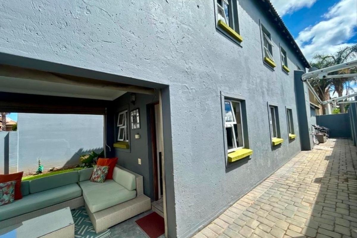 Exterior view of the townhouse featuring a paved side walkway and a covered patio area with access to the interior.