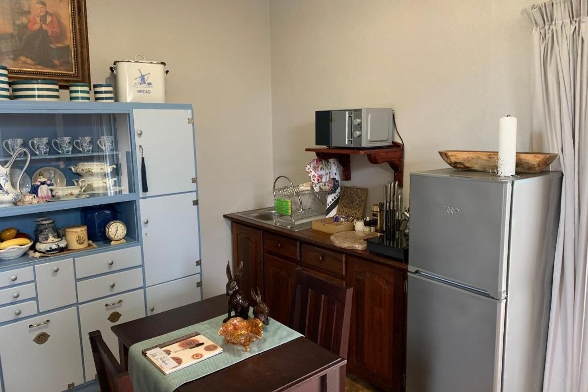 A compact kitchen area featuring wooden cabinetry, a stainless steel sink, and ample storage space, suitable for a small holding or cottage setting.
