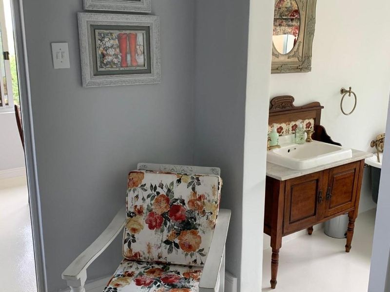 A view into a bathroom featuring a vintage-style wooden vanity cabinet with a ceramic basin and classic fixtures.