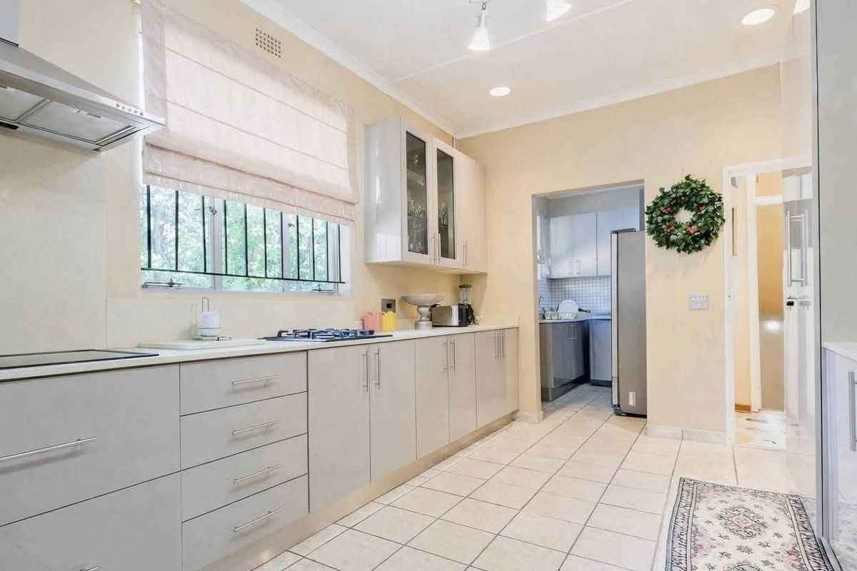 Modern kitchen featuring sleek cabinetry, integrated hob, extractor fan, and tiled flooring, with an adjacent scullery area for additional utility and storage.
