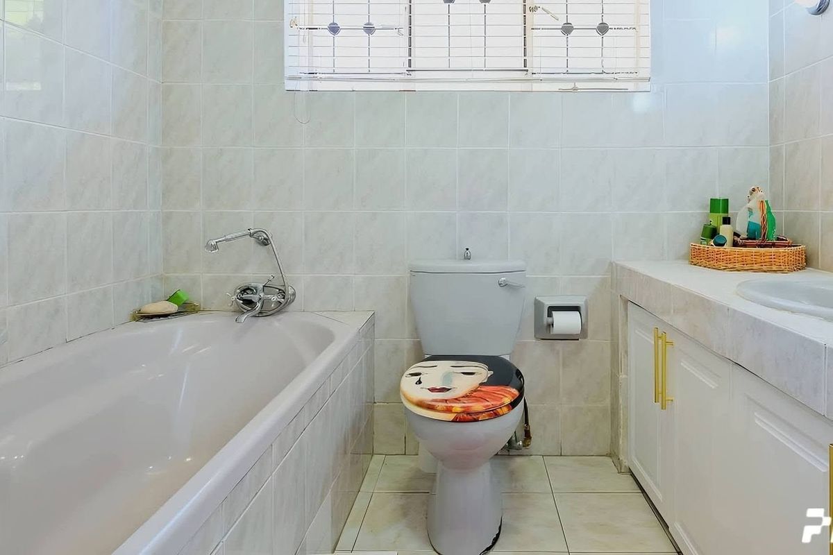 A functional bathroom featuring a built-in bathtub, a standard toilet, and a vanity unit with integrated basin and storage cabinetry.