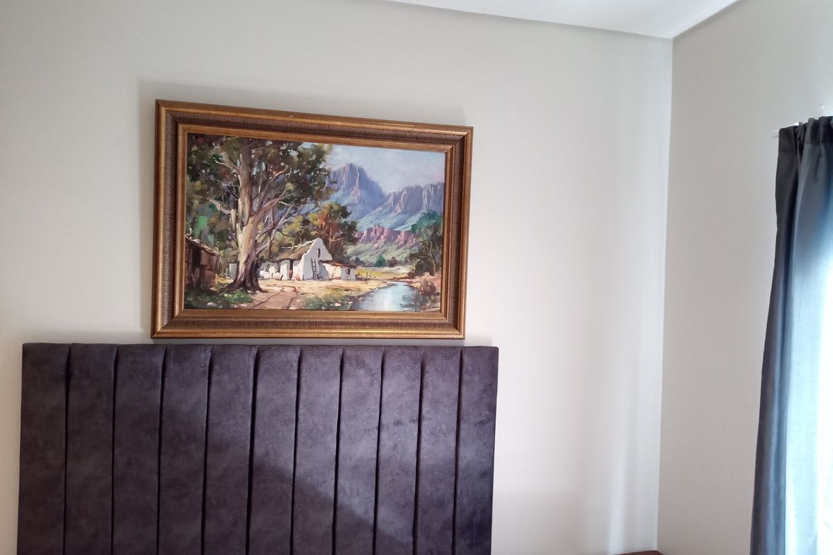A bedroom interior featuring neutral wall finishes and a modern upholstered headboard.
