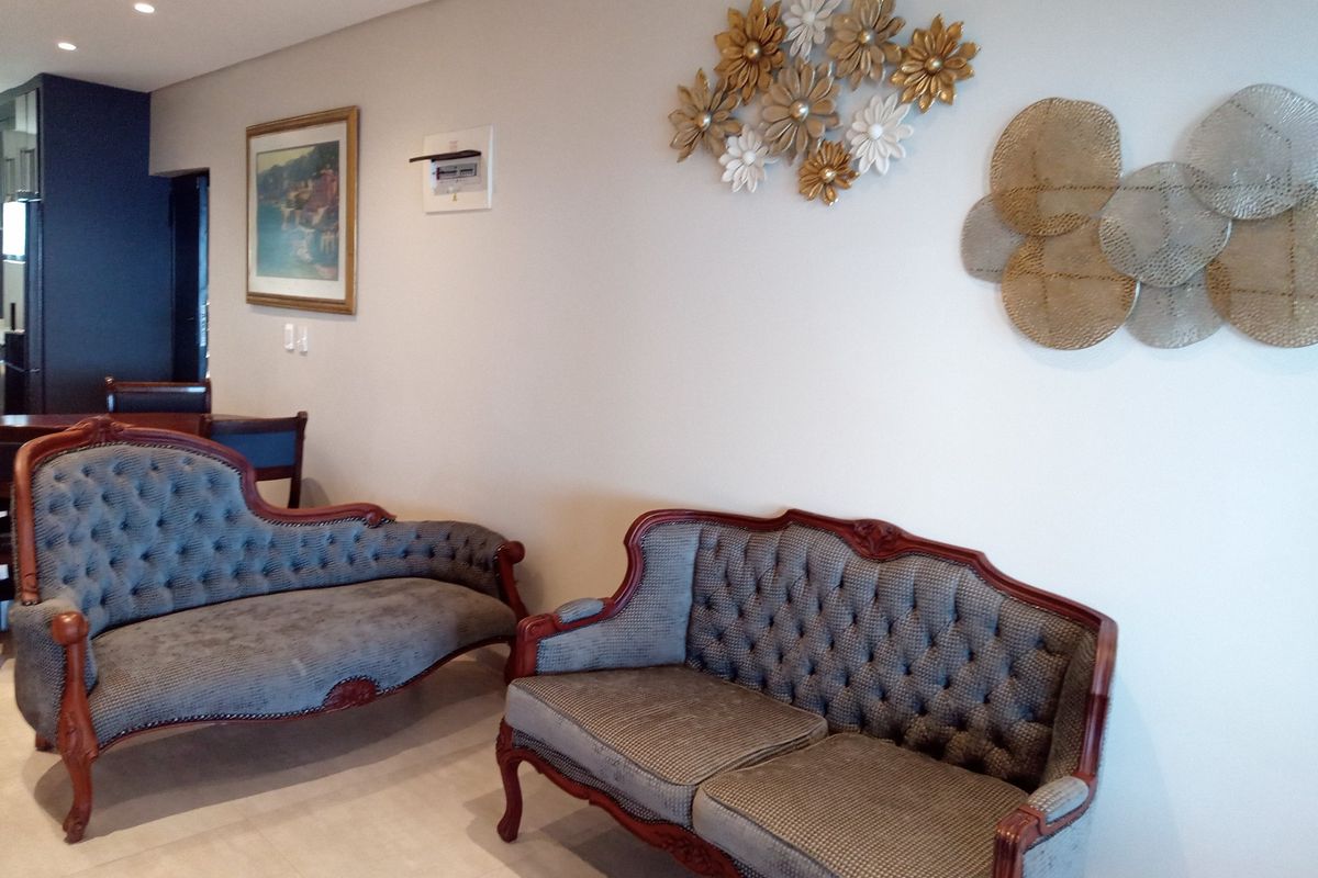 A well-maintained living area featuring neutral tiled flooring, recessed ceiling lighting, and a clean, modern aesthetic.