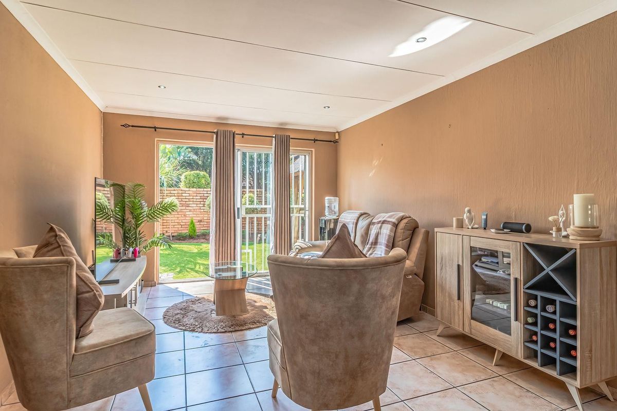 A comfortable living room featuring tiled flooring, recessed ceiling lighting, and sliding glass doors that provide direct access to the rear garden.
