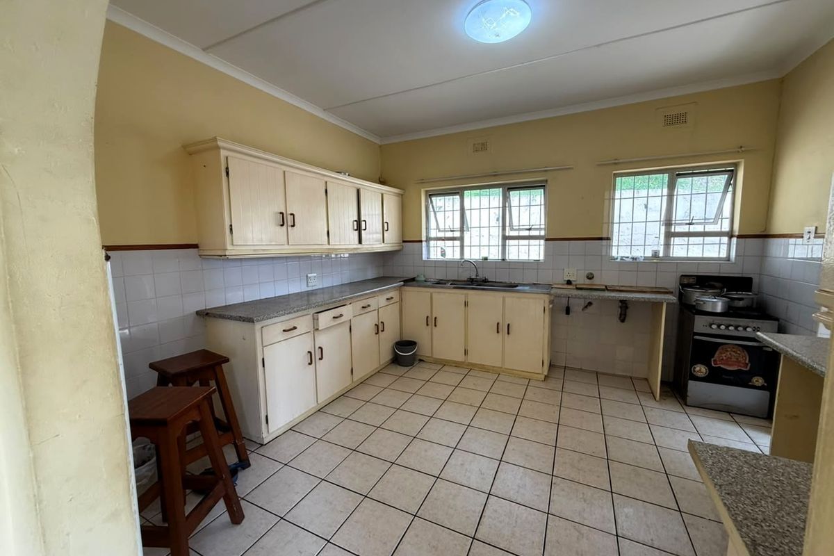 A functional kitchen featuring built-in cabinetry, laminate countertops, tiled splashbacks, and a freestanding stove, offering potential for modernization and aesthetic updates.