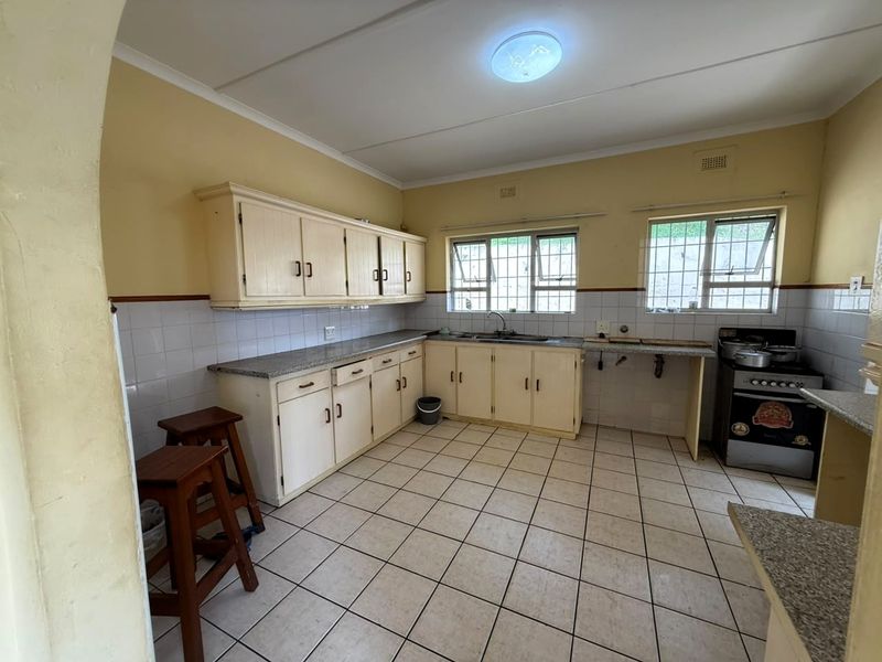 A functional kitchen featuring built-in cabinetry, laminate countertops, tiled splashbacks, and a freestanding stove, offering potential for modernization and aesthetic updates.
