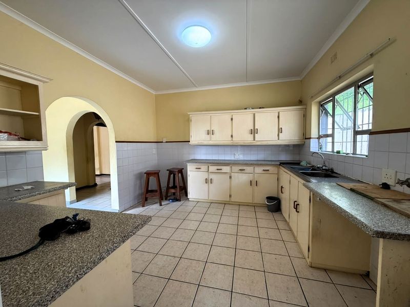 A functional kitchen featuring built-in cabinetry, granite countertops, and a double basin sink, offering a classic layout with potential for modern updates.