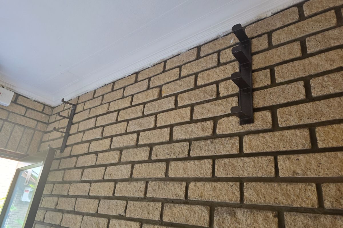 A close-up view of an interior wall featuring exposed face brickwork and decorative wall-mounted brackets, finished with a white ceiling cornice.
