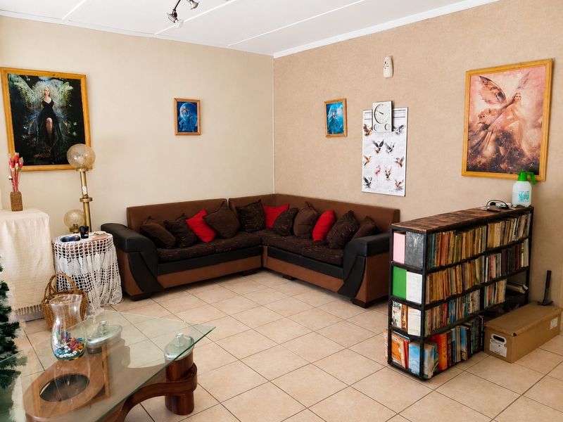 A living room featuring neutral wall finishes and ceramic floor tiles, providing a functional and well-lit space for relaxation.