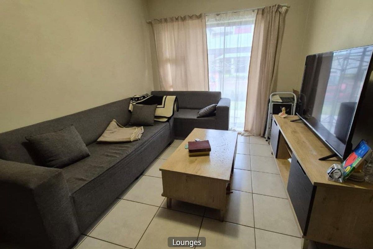 A functional living room featuring tiled flooring and a sliding glass door providing natural light.
