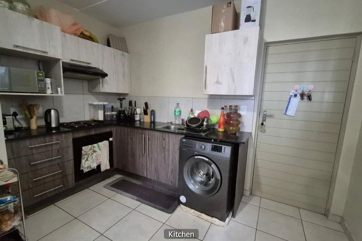 Compact kitchen featuring dark wood-look lower cabinetry, light wood-look upper cabinets, granite countertops, built-in oven, extractor fan, and tiled flooring.