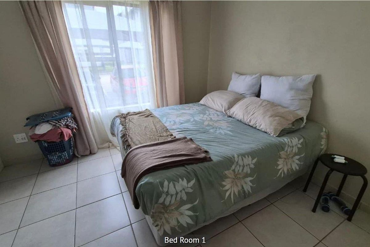 A bedroom featuring tiled flooring and a large window with curtains, providing natural light.