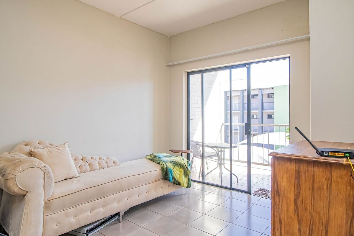 A bright living area featuring tiled flooring and large sliding glass doors that provide direct access to a private balcony.