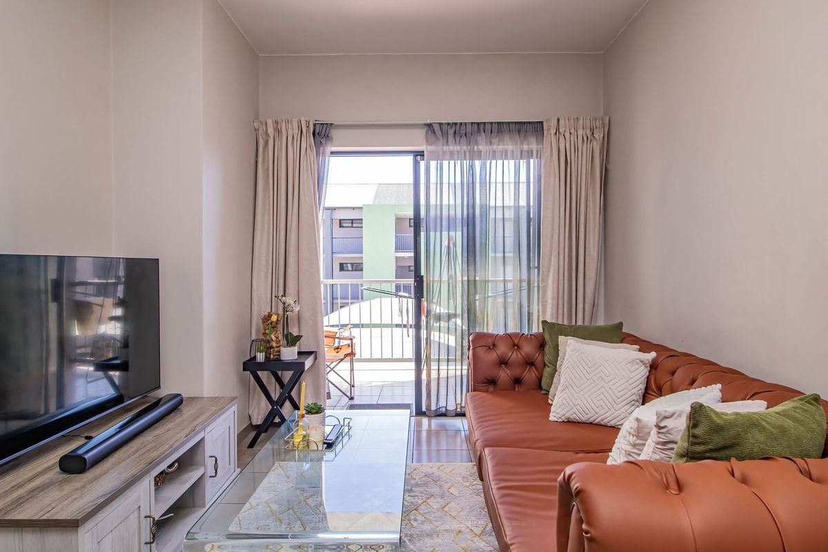 A comfortable living room featuring tiled flooring and a sliding glass door that opens onto a private balcony.