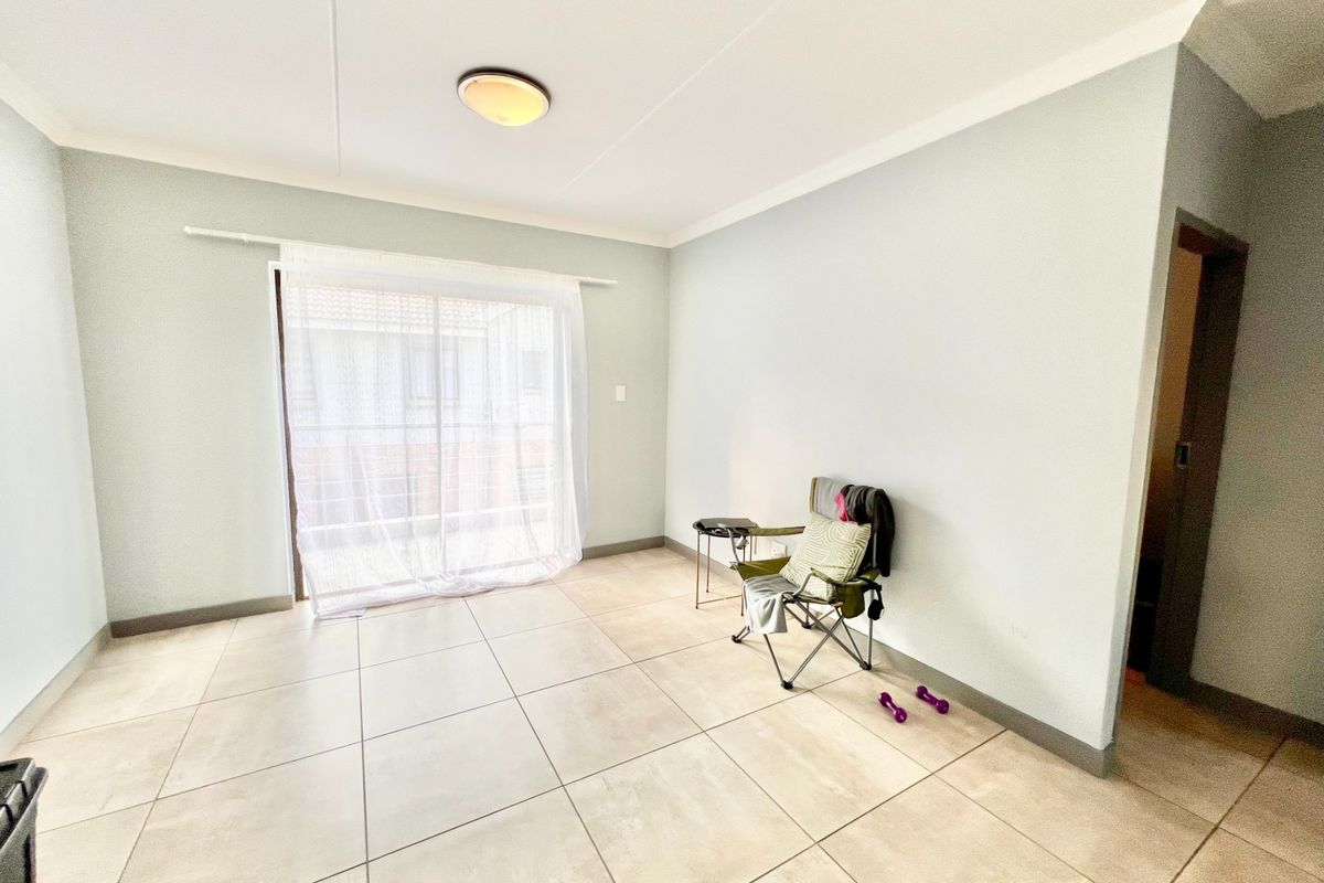 A bright, open-plan living area featuring large format floor tiles and a sliding glass door leading to an outdoor space.