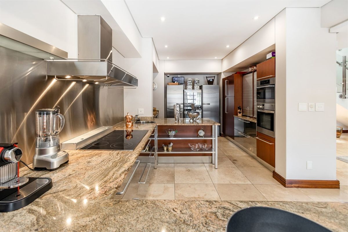 Modern kitchen featuring granite countertops, stainless steel splashback, built-in appliances, and tiled flooring with recessed lighting.