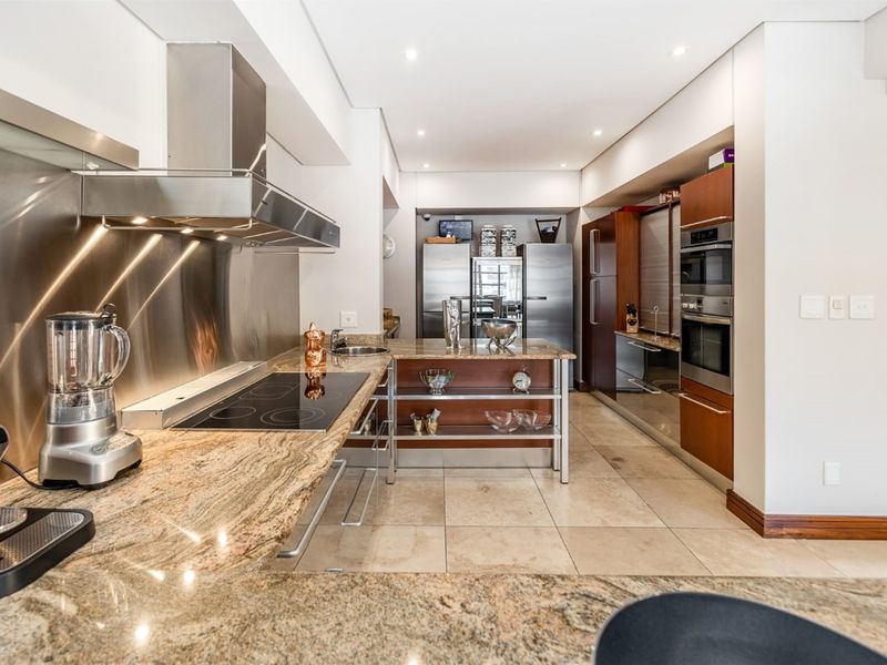 Modern kitchen featuring granite countertops, stainless steel splashback, built-in appliances, and tiled flooring with recessed lighting.