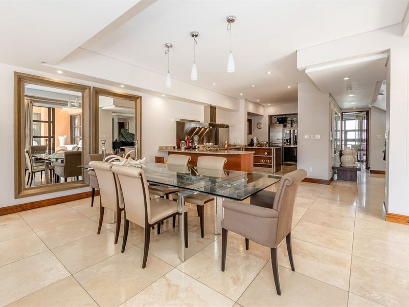 Spacious open-plan dining and kitchen area featuring polished stone flooring, modern pendant lighting, and a functional kitchen island with integrated cabinetry.