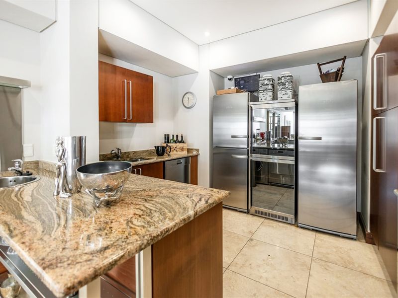 A well-appointed kitchen featuring granite countertops, ample built-in cabinetry, stainless steel fixtures, and tiled flooring, offering a functional and modern workspace.