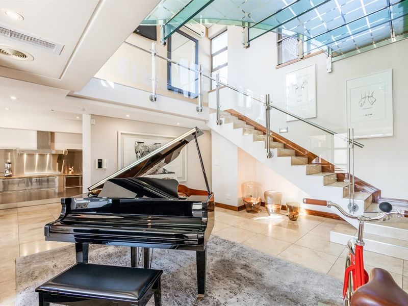 Spacious open-plan living area featuring a striking glass staircase, modern stainless steel kitchen finishes, and high-end architectural detailing throughout.