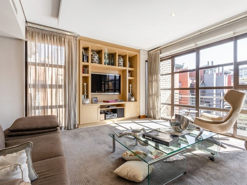 A bright and spacious living room featuring custom built-in cabinetry and expansive floor-to-ceiling windows that provide ample natural light.