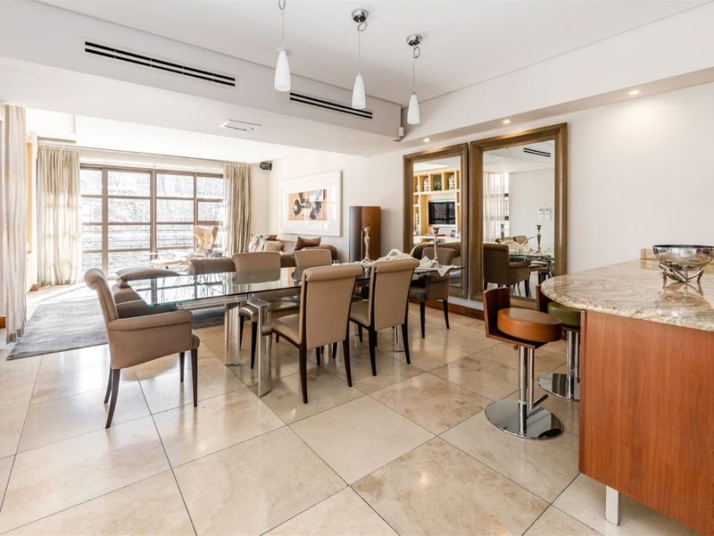 Spacious open-plan living and dining area featuring stone flooring, ducted air conditioning, and large glass doors leading to an outdoor space.