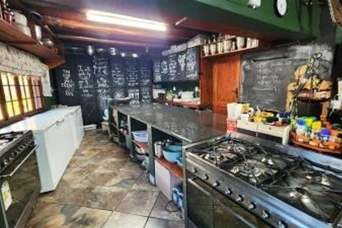 A rustic, industrial-style kitchen featuring a large central island, dual gas stoves, and extensive chalkboard wall detailing.