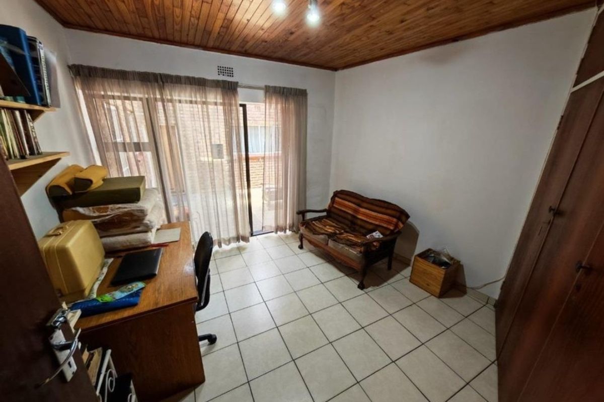 A bedroom featuring tiled flooring, a wooden ceiling, and sliding glass doors providing access to the exterior.