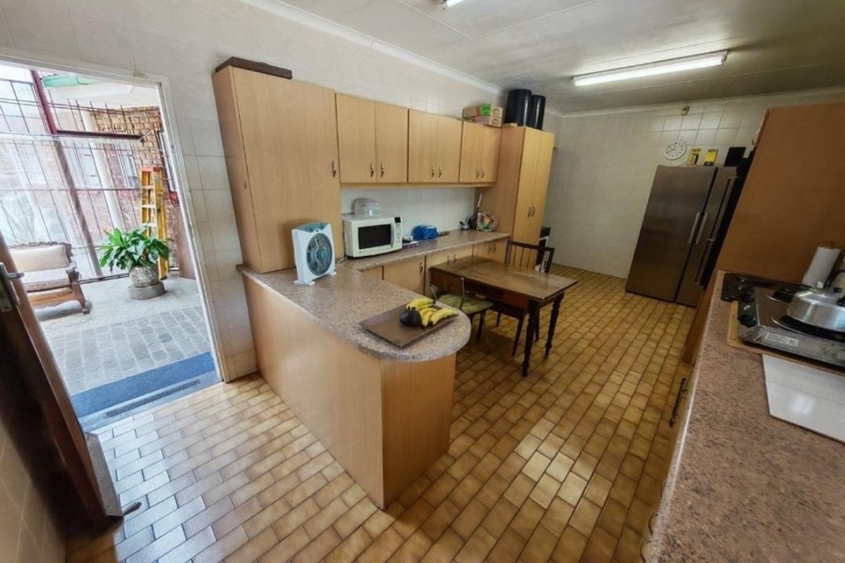 A functional kitchen featuring laminate cabinetry, stone-look countertops, and tiled flooring, with direct access to an outdoor patio area.