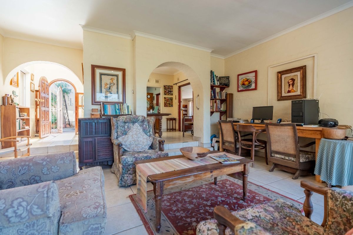 A living room featuring arched doorways, tiled flooring, and built-in shelving, providing access to an adjacent outdoor patio area.
