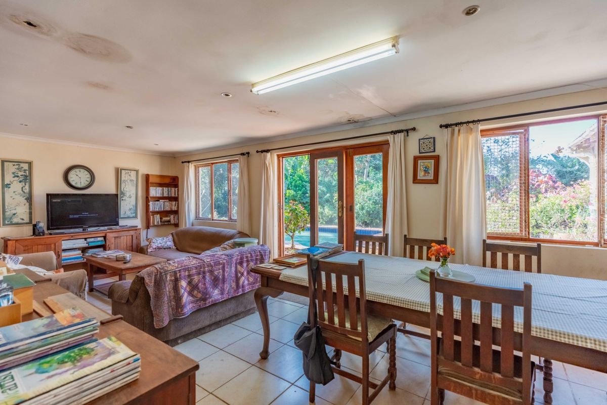 Open plan living and dining area featuring tiled flooring, large windows, and sliding glass doors providing direct access to the outdoor pool area.
