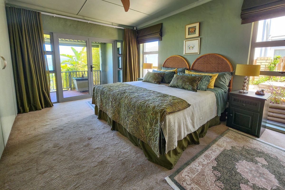 Spacious bedroom featuring neutral carpeting, ceiling fan, and large glass sliding doors providing direct access to an outdoor balcony area.