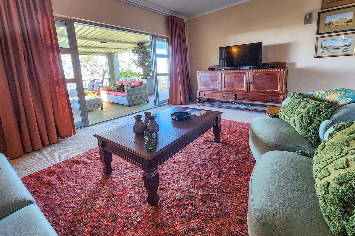 A comfortable living room featuring large sliding glass doors that open onto a covered patio, providing seamless indoor-outdoor flow and natural light.