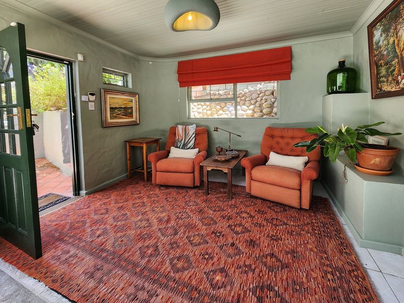 A cozy living room featuring sage green walls, a beadboard ceiling, and direct access to an outdoor patio area.