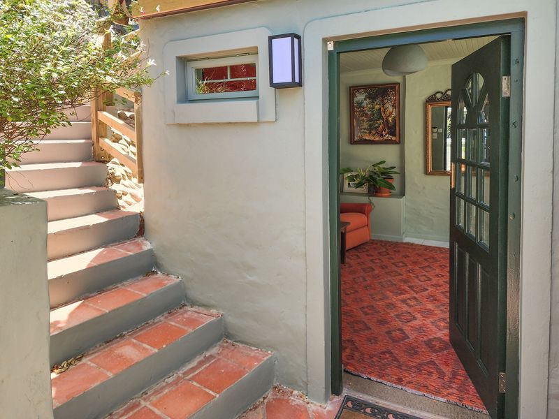 An exterior view showing a terracotta tiled staircase leading to an entrance door, with a glimpse into the interior living space.