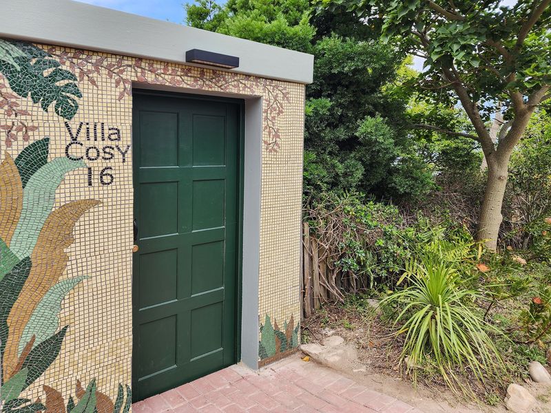 A unique exterior entrance featuring decorative mosaic tile work on the facade and a solid green panelled door.