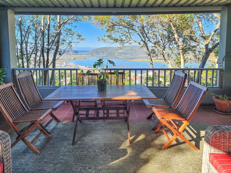A covered patio area featuring tiled flooring and a metal balustrade, offering expansive views of the estuary and surrounding landscape.