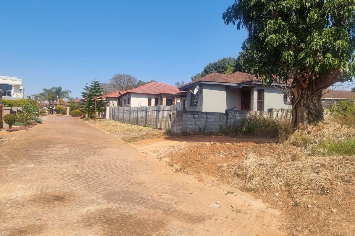 A street view of a residential neighborhood featuring paved roads, perimeter fencing, and established housing in a suburban setting.
