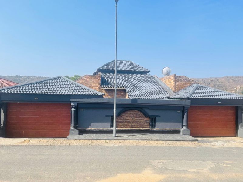 Front elevation of a residential property featuring two integrated garages with wood-look doors and a decorative brick and rendered facade.