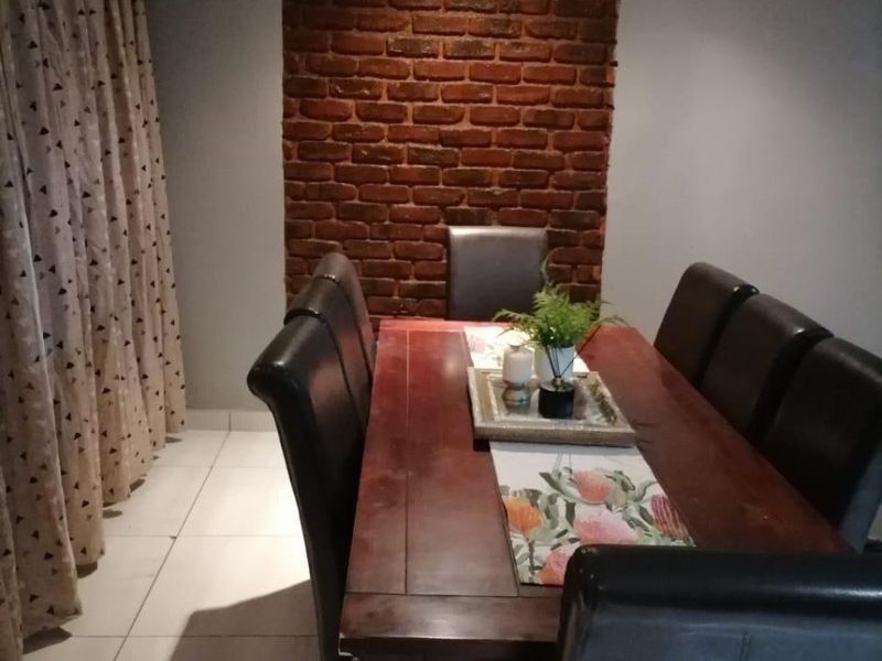 Dining room featuring tiled flooring and a decorative exposed brick feature wall.