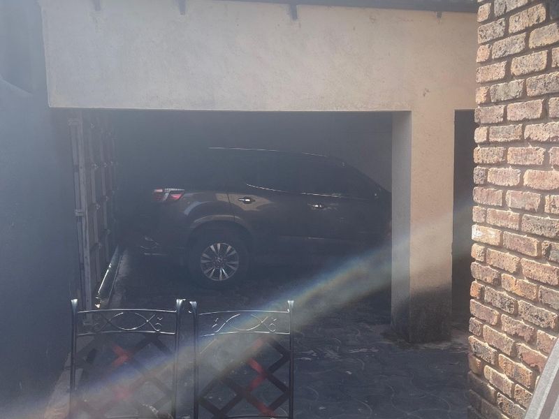 A view of the garage entrance featuring a paved driveway area and brick masonry detailing.