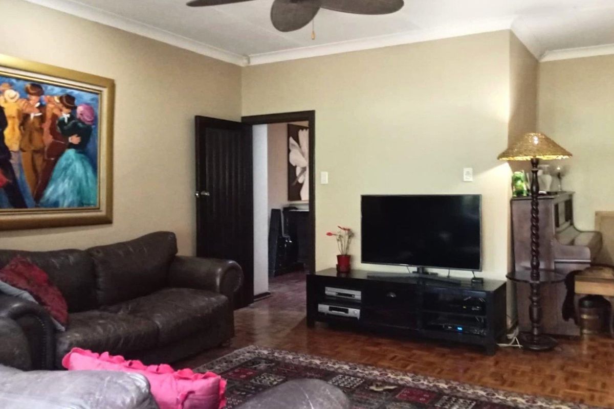 A living room featuring parquet flooring, a ceiling fan, and a doorway leading to an adjacent room.